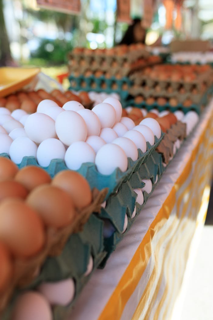 Close-up of white and brown eggs in cartons at an outdoor farmer's market stall.